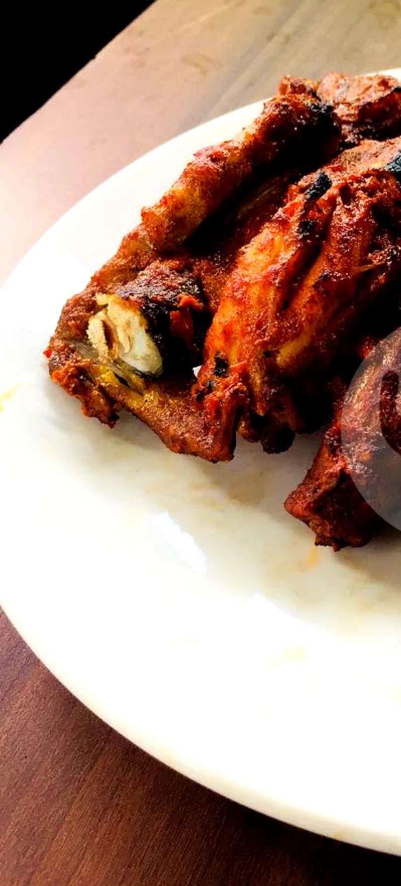 Ayam taliwang bakar dengan bumbu merah pekat di atas piring putih